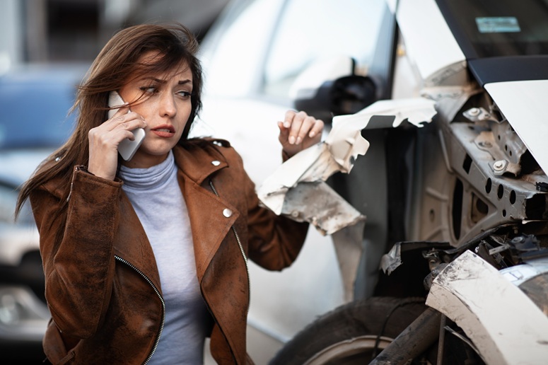 woman inspecting damaged car